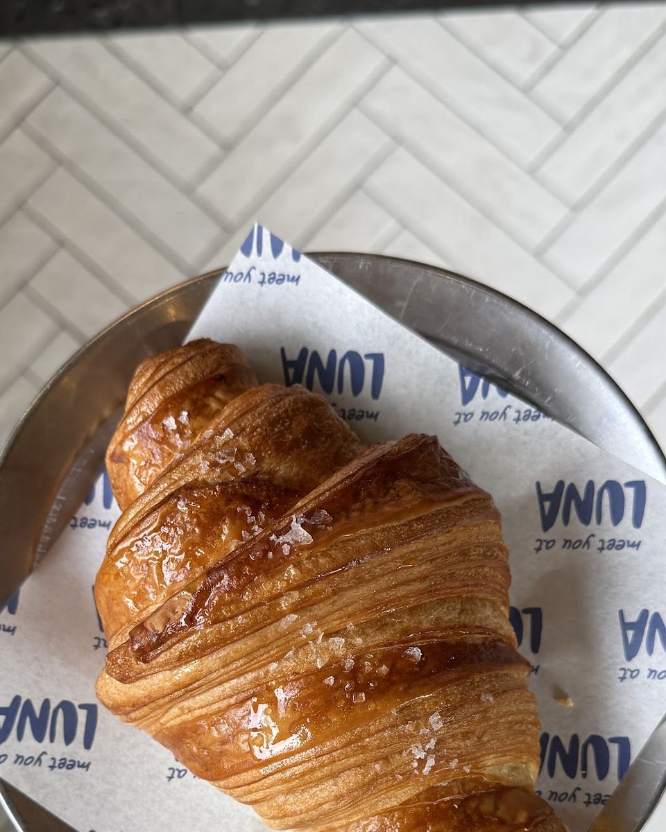 A croissant on a metal tray lined with LUNA paper
