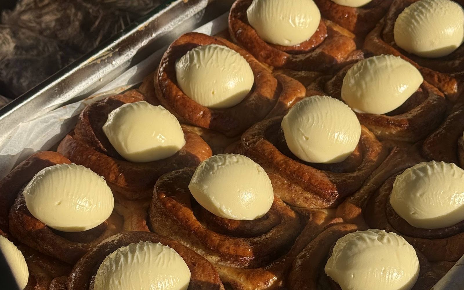 A tray of cinnamon buns topped with cream icing